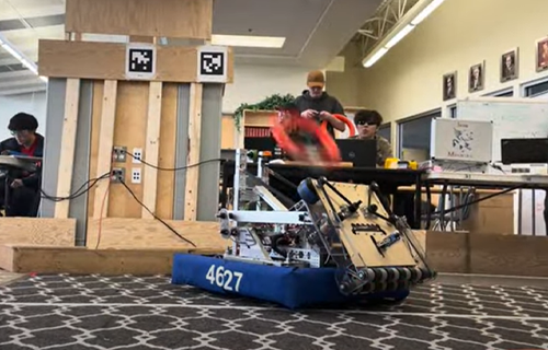 A robot shooting a orange hoop into the bin for the practice competition